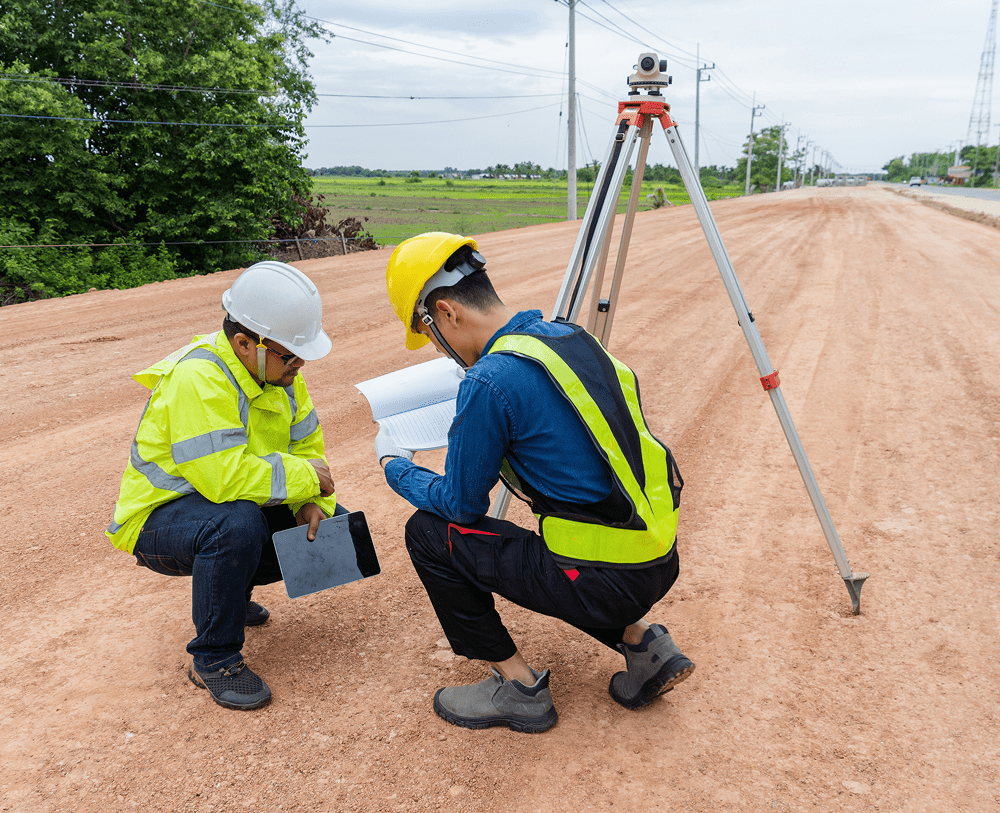 Surveyors examining documents on dirt road