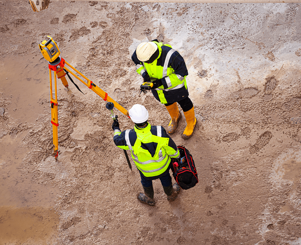 Workers using surveying equipment outdoors
