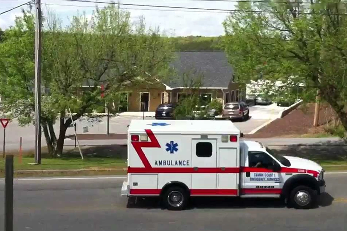 Ambulance driving on suburban road, daytime.