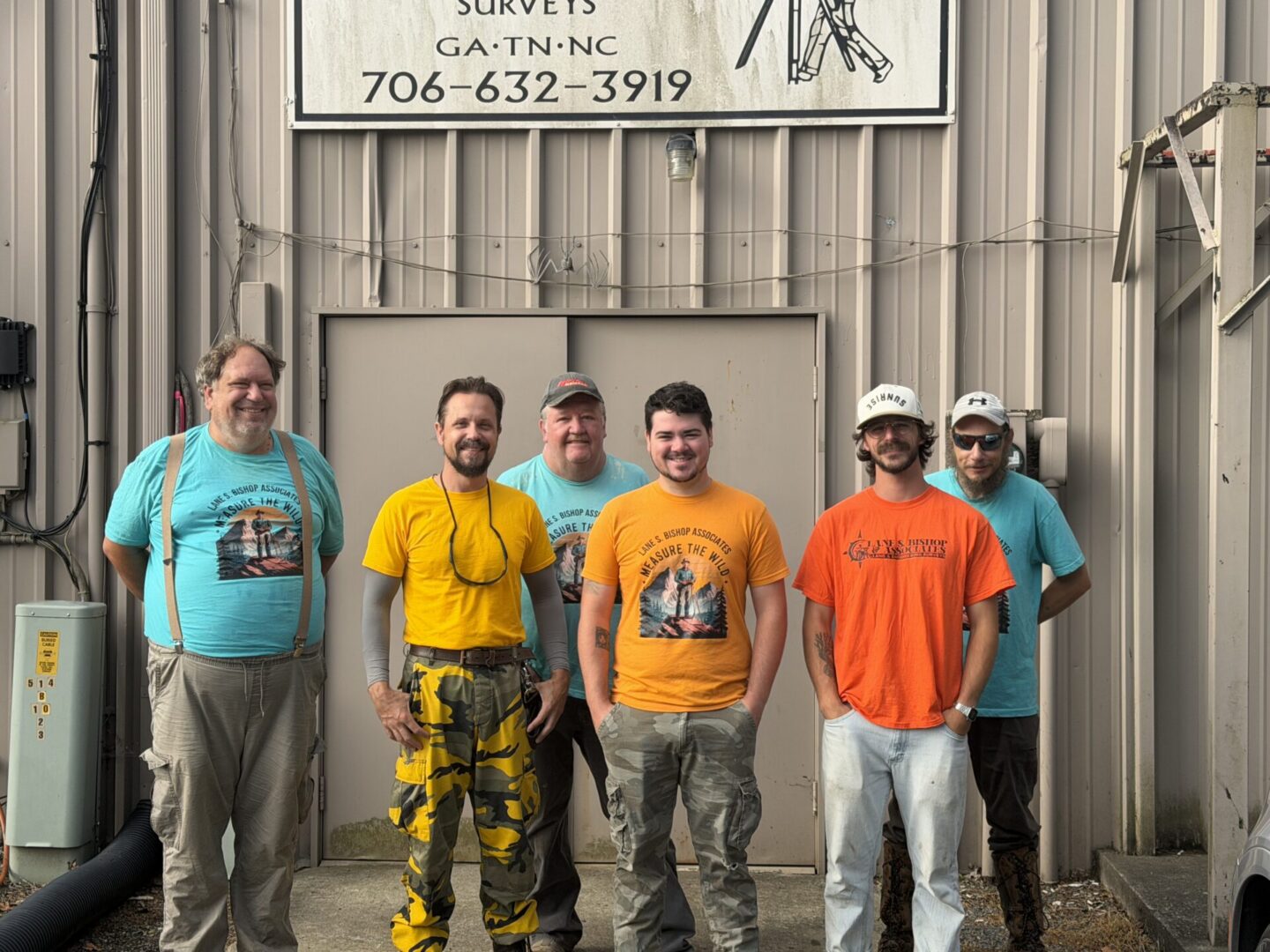 Group of six men standing outside building.