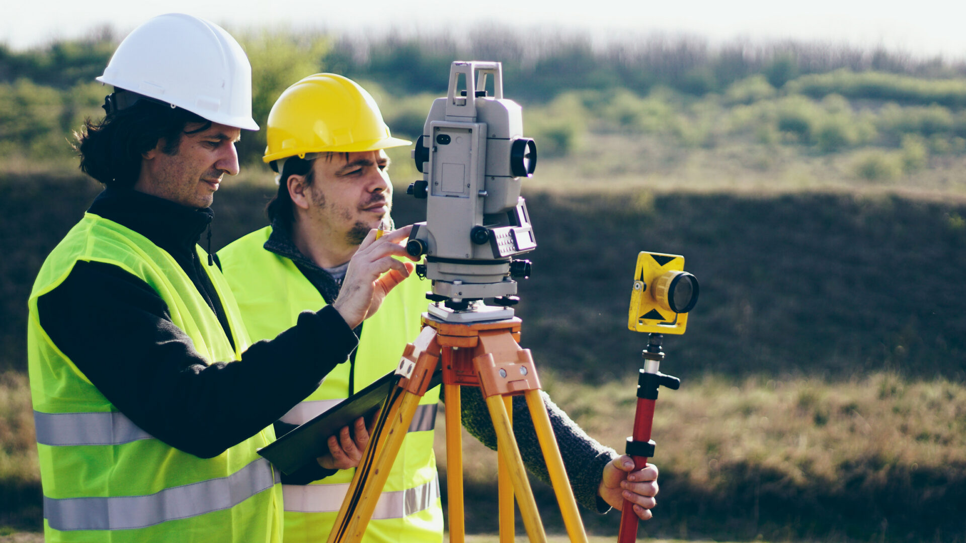 Surveyors using equipment in a field setting.